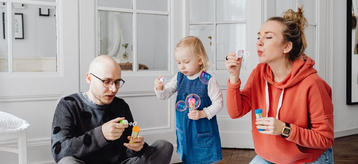 Family enjoying quality time blowing bubbles indoors, capturing joyful moments.