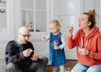 Family enjoying quality time blowing bubbles indoors, capturing joyful moments.